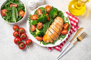 Pişmiş tavuk fileto ve taze sebze salatası. Tavuk göğsü ve yeşil sebzeler masada. Sağlıklı yemek, keto diyeti konsepti. Sağlıklı yemek adamları.