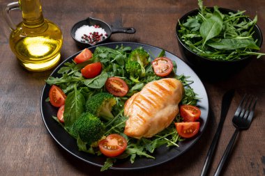 Fırında tavuk filetosu ve taze sebze salatası. Tavuk göğsü ve yeşil sebzeler ahşap masada. Sağlıklı yemek, keto diyeti konsepti. Sağlıklı yemek adamları.