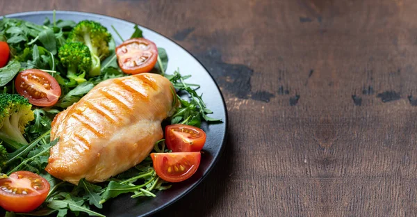 Grilled chicken breast, chicken fillet and fresh vegetable salad, broccoli closeup on wooden table. Healthy lunch menu. Healthy food, keto diet, dieting concept