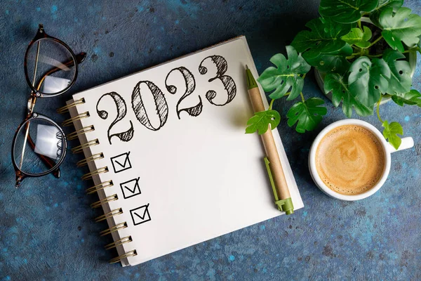 New year resolutions 2023 on desk. 2023 resolutions list with notebook, coffee cup on table. Goals, resolutions, plan, action, checklist concept. New Year 2023 template, copy spac