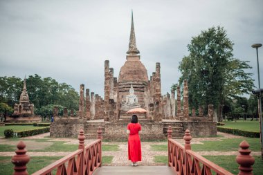 Tayland 'ın Sukhothai eyaletinde yağmurlu bir mevsimde Wat Mahathat tapınağının önünde duran Lanna tarzı şemsiyeli bir kadının manzarası..