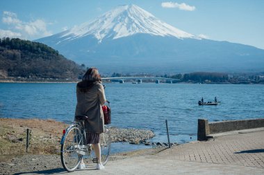 Bir kadın bisikletini park ediyor ve Kawaguchi Gölü 'nde Fuji Dağı' nın arkasında fotoğraf çekiyordu, Yamanashi, Japonya.