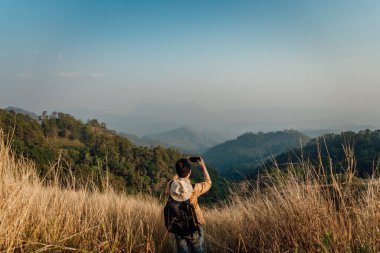 Beyaz şapkalı sarı gömlekli bir adam cep telefonuyla Hadubi, Chiang Mai, Tayland 'daki altın çayırlarda fotoğraf çekiyor..