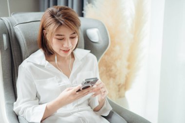 Oturma odasında masaj koltuğunda oturup müzik dinleyen bir kadın..