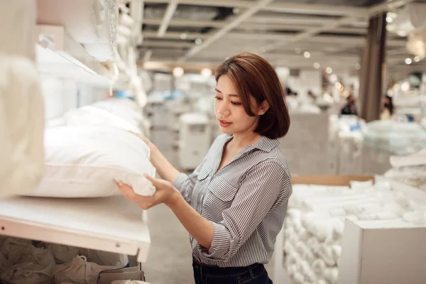 Asyalı bir kadın alışveriş merkezinde yastık seçiyor..