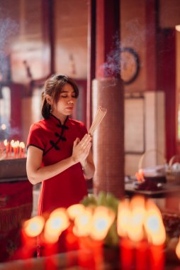 An Asian woman lighting incense sticks to pay homage to the Chinese New Year.