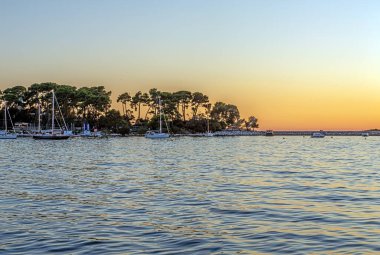 Yazın rıhtımlı bir adayla denizde gün batımının görüntüsü.