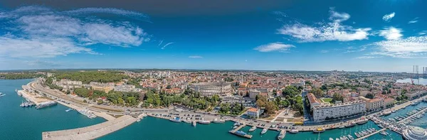 Drone panorama of the Croatian coastal city of Pula taken during the day above the harbor in summer