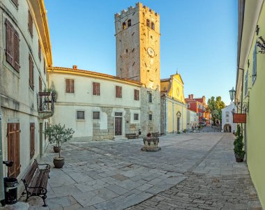 Motovun merkez meydanındaki panorama. St. Stephen Kilisesi ve şehir kapısı. Yazın gündoğumunda.