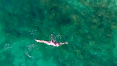 Güneşli bir yaz gününde denizde yüzen çıplak bir kadının robot videosu.