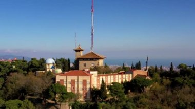 Tibidabo üzerinde gündüz açık havada Barselona üzerinde muhteşem manzaralı dikey bir tırmanışın insansız hava aracı videosu