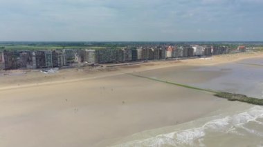 Belçika 'nın Middelkerke sahil kasabasının sahil şeridindeki insansız hava aracı videosu yaz mevsiminde dalgalı sularda yüzüyor.