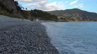 Yazın akşam çakıl taşlı bir plaja çarpan dalgaların yavaş çekim videosu.