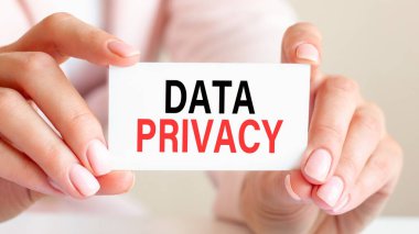 Veri gizliliği bir kadının elindeki beyaz kartvizitle yazılır. Pembe arka plan. İş ve reklam kavramı