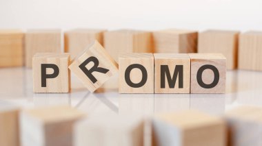 Promo. Gri arka planda harfleri olan ahşap bloklar. Tablonun aynalı yüzeyindeki başlığın yansıması. Seçici odak.