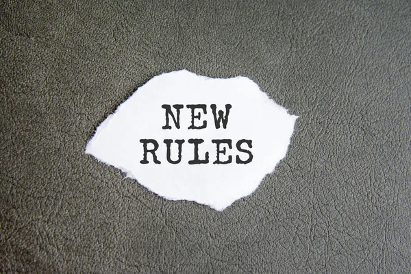 NEW RULES sign on the torn paper on the gray background, business concept