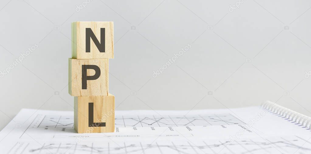 NPL wooden blocks are on the paper gray background. business concept. space for text in right. front view. NPL - short for non performing loans