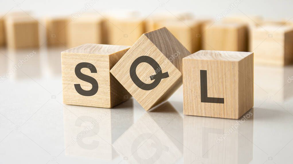 Three wooden cubes with the letters SQL on the bright surface of a gray table. the inscription on the cubes is reflected from the surface of the table. SQL - short for Structured Query Language