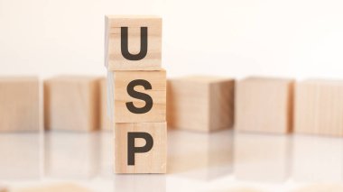 USP harfli tahta küpleri dikey bir piramide yerleştirilmiş, arka planda, yansıma yüzeyinde, iş konseptinde. USP, eşsiz satış önerisinin kısaltılmışı