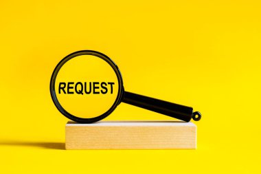 Sarı arka plandaki büyüteç vasıtasıyla yazma talebi. Büyüteç bir masanın üzerinde tahta bir standa monte edilir.