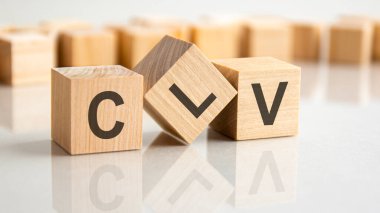 Gri bir masanın parlak yüzeyinde CLV harfleri olan üç tahta blok. Küplerdeki yazıtlar masanın yüzeyinden yansıyor. clv - Müşteri yaşam süresi değeri