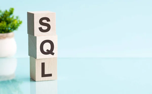 木制立方体与字母Sql在垂直金字塔 蓝色背景 反映从表面的桌子 商业概念 Sql 结构化查询语言的缩写 — 图库照片