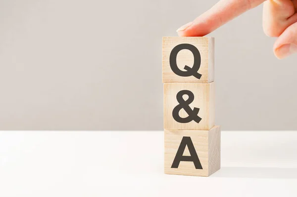 QとAの文字で木の立方体ブロックを手で握る。金融、経営、経済、ビジネスの概念 — ストック写真