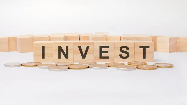 Investment concept. Wooden block with the text invest on wooden white boards — Stock Photo, Image