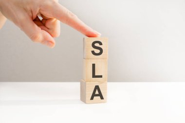 SLA metniyle el ele tutuşan tahta küp bloğu. Finansal, yönetim, ekonomik, iş konsepti. SLA - hizmet seviyesi anlaşmasının kısaltılmışı.