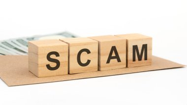 Tahta bloklar, üzerinde yazı olan bir zarf üzerinde dolandırıcılık, masanın üzerinde para, gri arka plan.