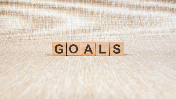 целей, написанных в деревянных кубиках. концептуальное слово, собранное из деревянных элементов с буквами. фондовое изображение, коричневый фон