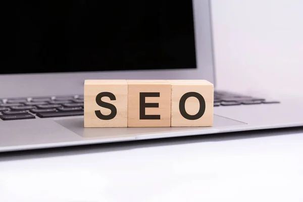 SEO - wooden cubes with letters on a silver laptop keyboard. SEO - short for Search Engines Optimization. business conceptual word collected of of wooden elements with the letters.