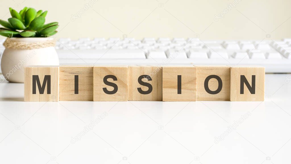 mission word made with wooden blocks. front view concepts, green plant in a flower vase and white keyboard on background