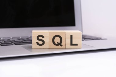SQL - gümüş dizüstü bilgisayar klavyesinde harfleri olan tahta küpler. SQL - Yapılandırılmış Sorgu Dili 'nin kısaltması. Harflerle ahşap elementlerin toplandığı iş kavramsal sözcükleri.