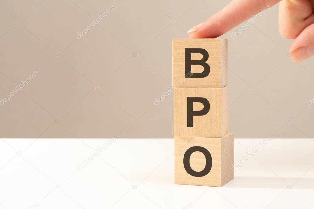 three wooden cubes with the letters BPO on the bright surface of a gray table