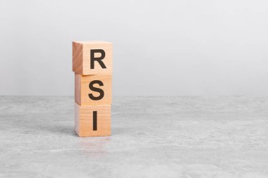 Beyaz bir masada üzerinde RSI yazılı tahta bir küp. İş konsepti, finans, yatırım, ekonomi. Tasarım için sağdaki boşluğu kopyala, gri arkaplan. RSI - Göreceli Kuvvet İndeksinin kısaltması