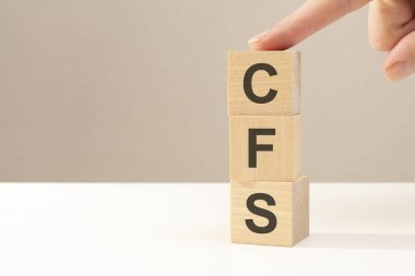 El, CFS harfinin yanına tahta bir küp koyuyor. Konsolide Finansal İfadenin kısaltması. İş konsepti. Soldaki metin için boşluk. ön görünüm