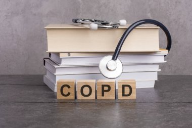 Copd kelimesi, gri bir arka planda steteskopun yanındaki tahta küplere yazılır. Hastane, klinik ve tıbbi işler için tıbbi konsept. Kitap ve steteskopla tıp eğitimi kavramı