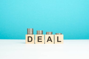 Anlaşma kavramı. Tahta sehpanın üzerinde yazı ve bozuk paralar olan tahta bloklar. kopyalama alanı. mavi arkaplan