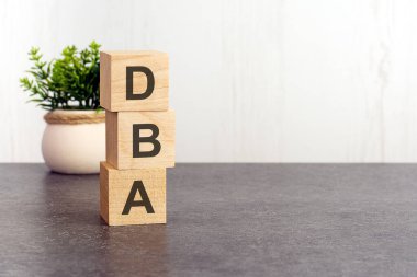 Tahta küplerde dba alfabesinin harfleri, beyaz arka planda yeşil bitki. dba - Veritabanı Yöneticisinin kısaltması