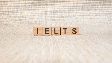 Kahverengi arka planda ahşap bloklarla yazılmış IELTS kelimesi, kavram. IELTS - Uluslararası İngilizce Test Sistemi 'nin kısaltması