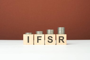Tahta bloklar üzerine IFSR metni, kahverengi arka planda madeni paralar, iş konsepti. IFSR - Sigorta Finansal Güç Beğeni 'nin kısaltması