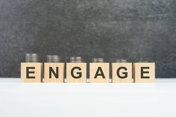 ДЕЛО, текст, написанный на деревянных кубиках со стопками монет разной высоты на каждом кубике на чёрном фоне, бизнес-концепция