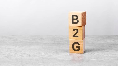 Beyaz bir masanın üzerinde b2g yazılı tahta bir küp. İş konsepti, finans, yatırım, ekonomi. Tasarım için sol taraftaki boşluğu kopyala, gri arkaplan. B2G - Hükümetin İş Yapma Kolaylığı