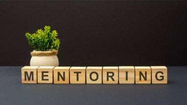 Ahşap küplere ve karanlık yüzeye akıl hocalığı alfabesinin harfleri. Yeşil bitki. siyah arkaplan