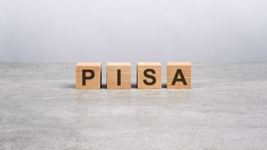 Parlak gri masanın üzerinde pida harfleri olan dört tahta blok. İş konsepti. pisa - uluslararası öğrenci değerlendirme programının kısaltılmışı