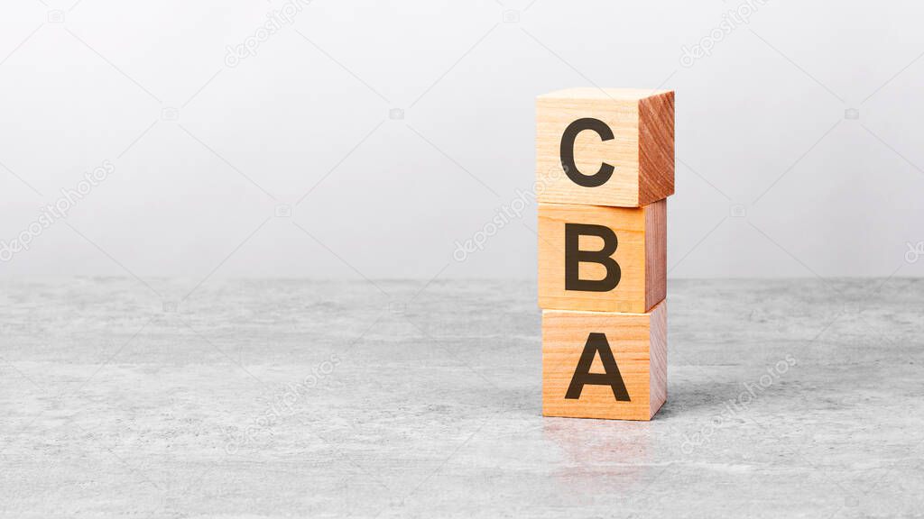 wooden cube on a white table with text cba. concept of business, financial, investment, economy. copy space on left for you design, gray background. CBA - short for Cost Benefit Analysis