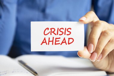 İlerideki kriz, bir kadının elindeki beyaz kartvizitte yazılı. Mavi arka plan. İş ve reklam kavramı