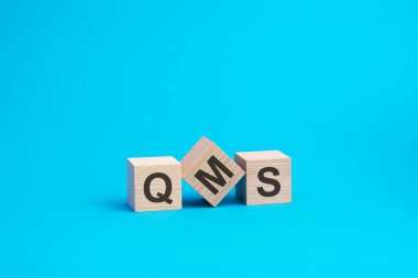 Tahta bloklar üzerine QMS metni, finansal iş konsepti, mavi arka plan. QMS - Kalite Yönetim Sistemi 'nin kısaltması