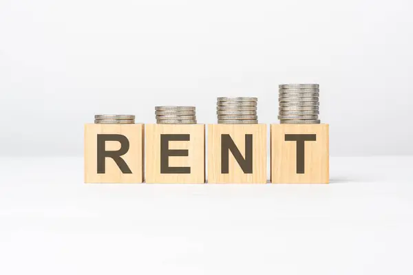 rent text written on wooden block with stacked coins on white background, growing trend, business concept